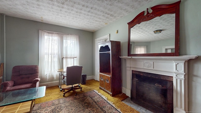 interior space with a tiled fireplace, baseboards, and a textured ceiling