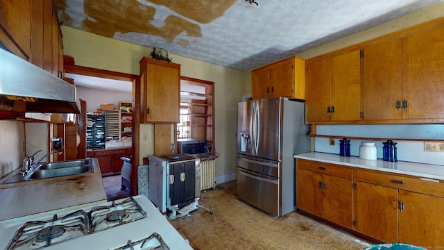 kitchen featuring stainless steel appliances, brown cabinetry, a sink, and light floors