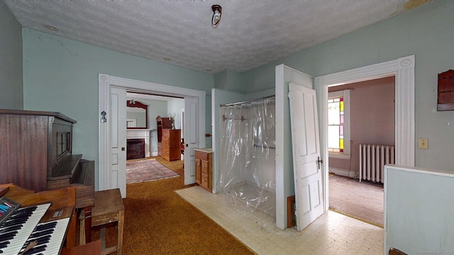 full bathroom featuring radiator, a fireplace, a textured ceiling, and a shower with shower curtain