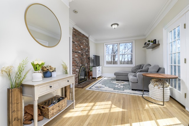 living area featuring light wood-type flooring, a brick fireplace, baseboards, and ornamental molding