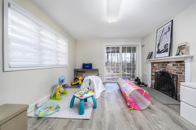 game room with a fireplace, baseboards, and wood finished floors