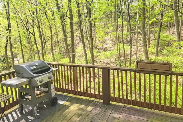 wooden deck with a grill and a wooded view