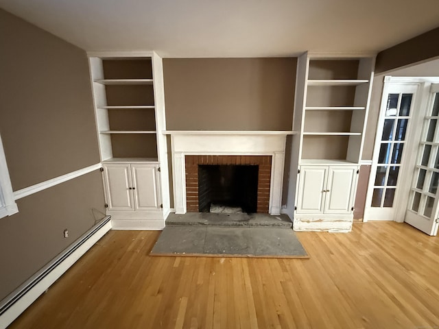 unfurnished living room featuring built in features, a brick fireplace, a baseboard heating unit, and wood finished floors