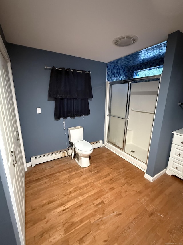 full bathroom featuring baseboard heating, wood finished floors, toilet, and a stall shower