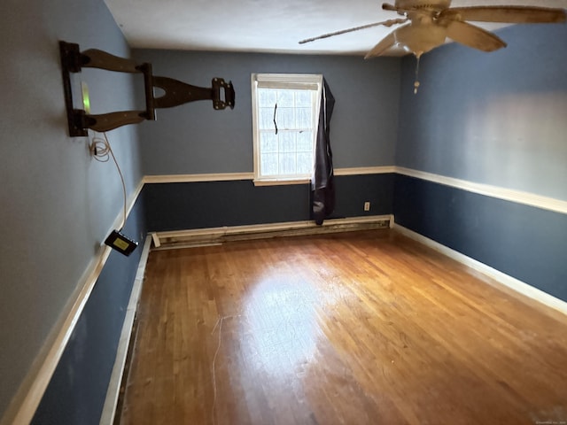 empty room featuring a ceiling fan, baseboards, and wood finished floors