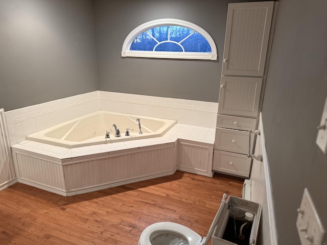 full bathroom with a whirlpool tub, a baseboard heating unit, and hardwood / wood-style floors