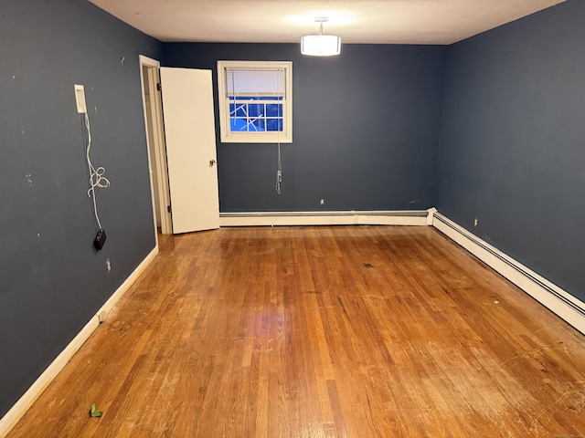 empty room with baseboards, baseboard heating, and wood finished floors