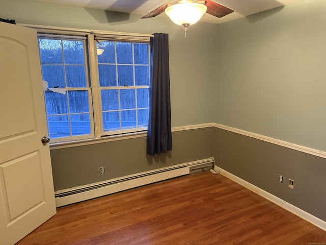 empty room featuring a ceiling fan, baseboards, baseboard heating, and wood finished floors