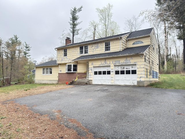 traditional-style home featuring a chimney, roof with shingles, aphalt driveway, and an attached garage
