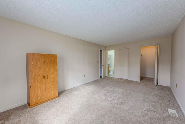 spare room featuring carpet, visible vents, a textured ceiling, and baseboards