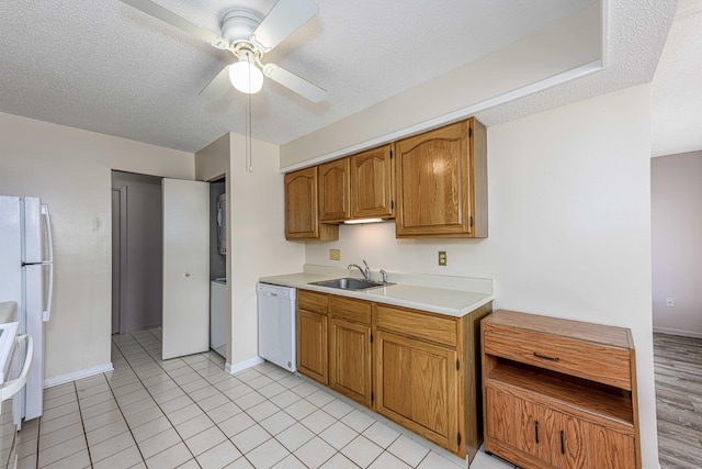 kitchen with white appliances, light countertops, a sink, and a textured ceiling