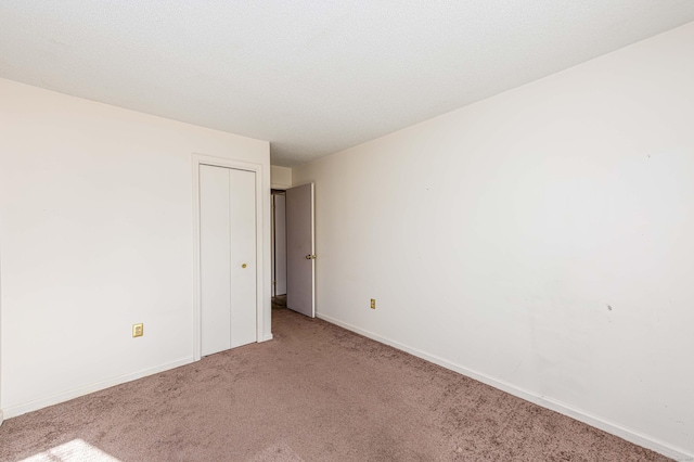 carpeted empty room featuring a textured ceiling and baseboards