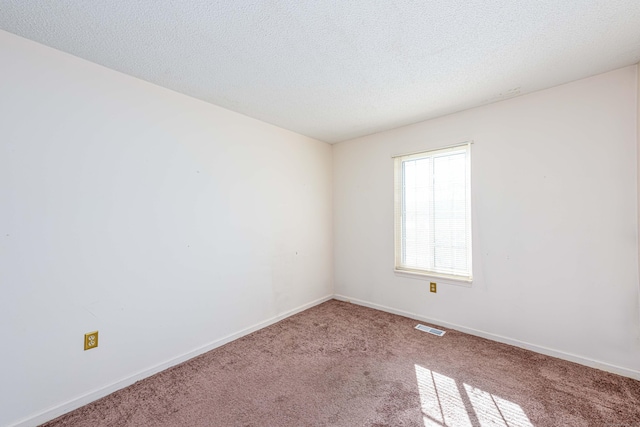 empty room with carpet floors, baseboards, visible vents, and a textured ceiling