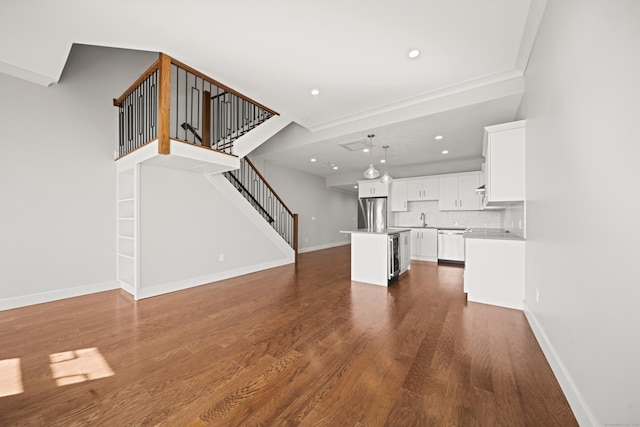 unfurnished living room featuring baseboards, dark wood-style floors, stairs, a sink, and recessed lighting