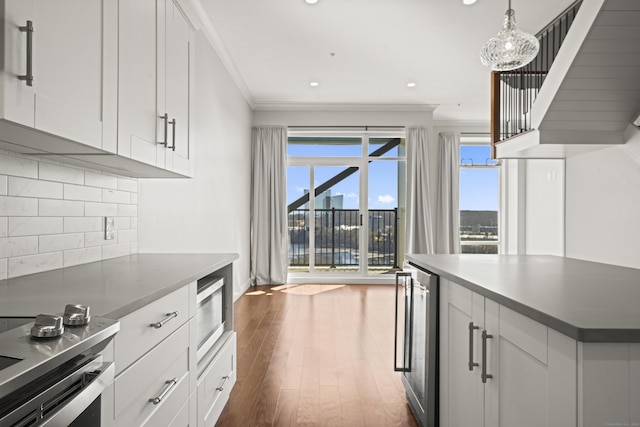 kitchen with wine cooler, dark wood finished floors, crown molding, stainless steel microwave, and decorative backsplash