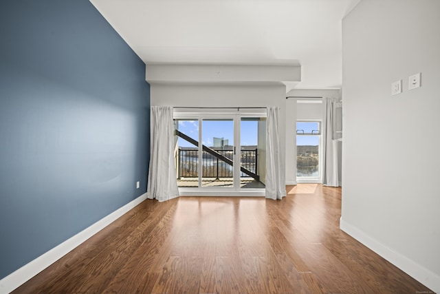 empty room with baseboards and wood finished floors