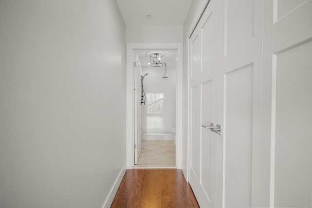 corridor featuring baseboards and wood finished floors