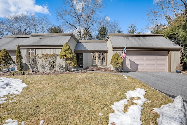 mid-century inspired home with a garage, aphalt driveway, a front yard, and a shingled roof