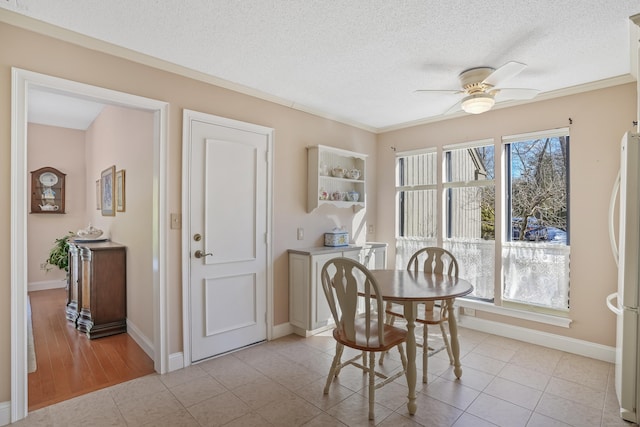 dining area featuring light tile patterned floors, a textured ceiling, baseboards, and a ceiling fan