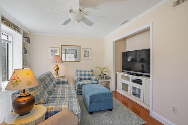 living room featuring wood finished floors, visible vents, and crown molding