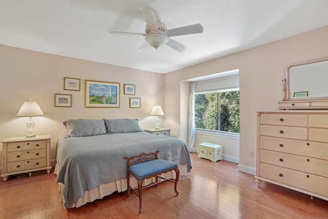 bedroom featuring a ceiling fan, a textured ceiling, baseboards, and wood finished floors