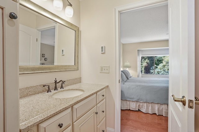 ensuite bathroom featuring vanity, ensuite bath, and wood finished floors