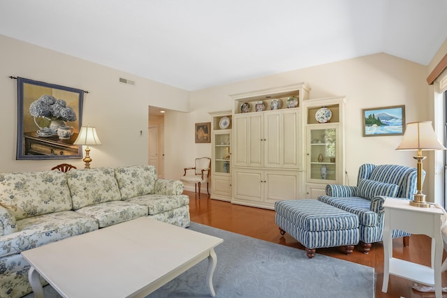 living room with visible vents, vaulted ceiling, and wood finished floors