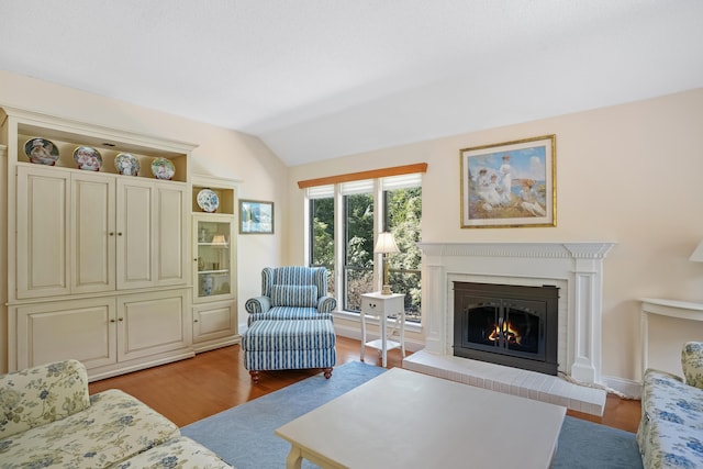 living area featuring a fireplace, vaulted ceiling, and wood finished floors