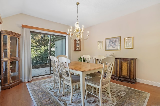 dining area with lofted ceiling, baseboards, a notable chandelier, and light wood finished floors