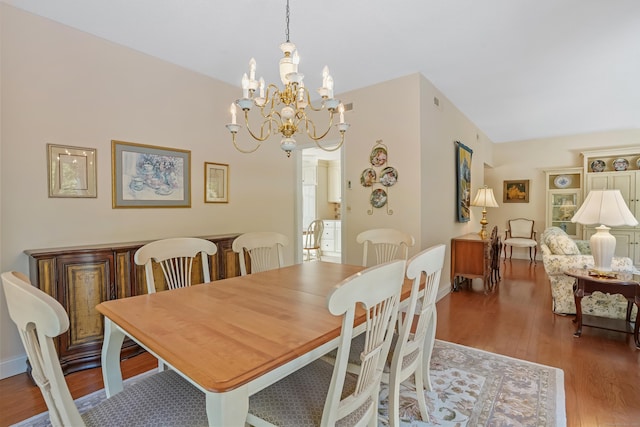 dining space with a chandelier, wood finished floors, and baseboards