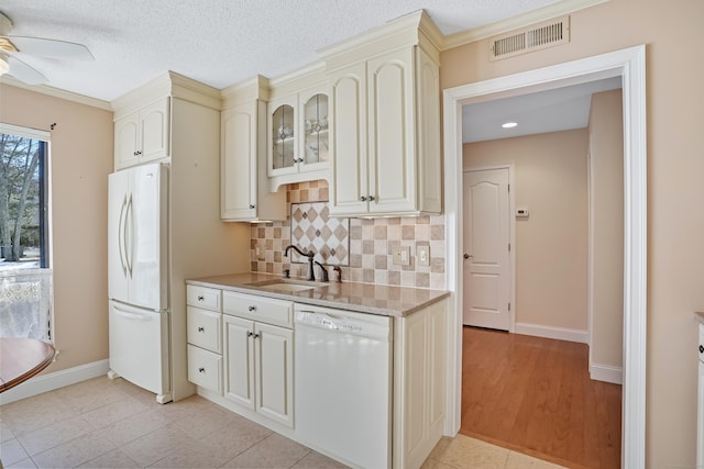 kitchen featuring white appliances, tasteful backsplash, visible vents, cream cabinetry, and a sink