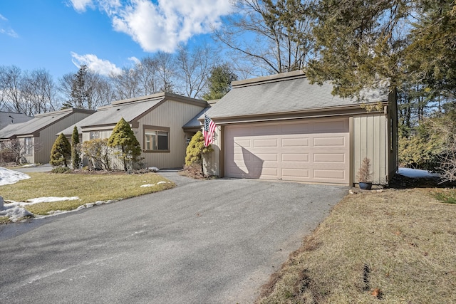 view of front facade featuring a garage, driveway, a shingled roof, and a front yard