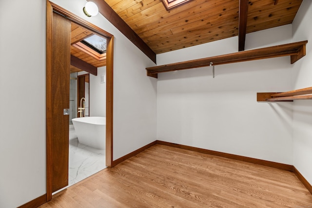 spacious closet with lofted ceiling with skylight and light wood-style floors