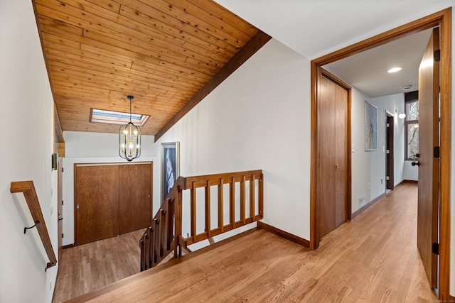 hallway featuring lofted ceiling, an upstairs landing, wood finished floors, wooden ceiling, and baseboards