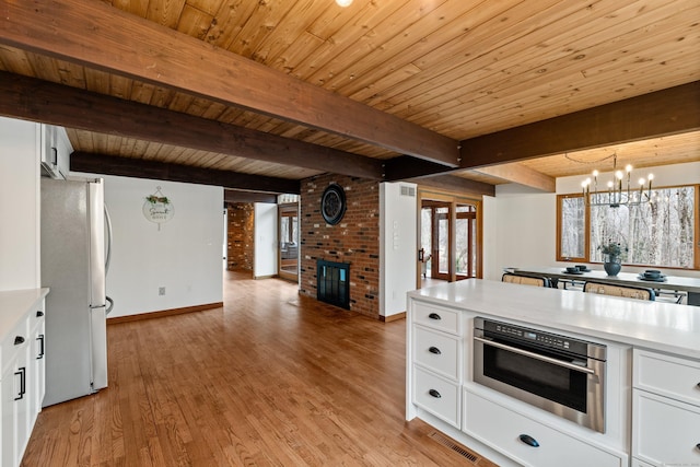 kitchen featuring a fireplace, white cabinetry, light countertops, appliances with stainless steel finishes, and light wood finished floors