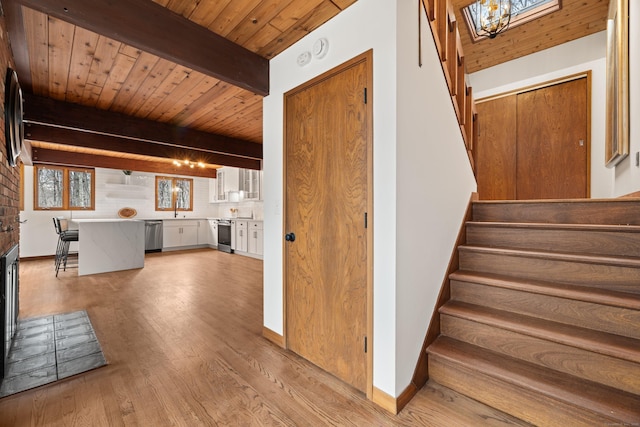 staircase featuring wood ceiling, baseboards, wood finished floors, and beamed ceiling