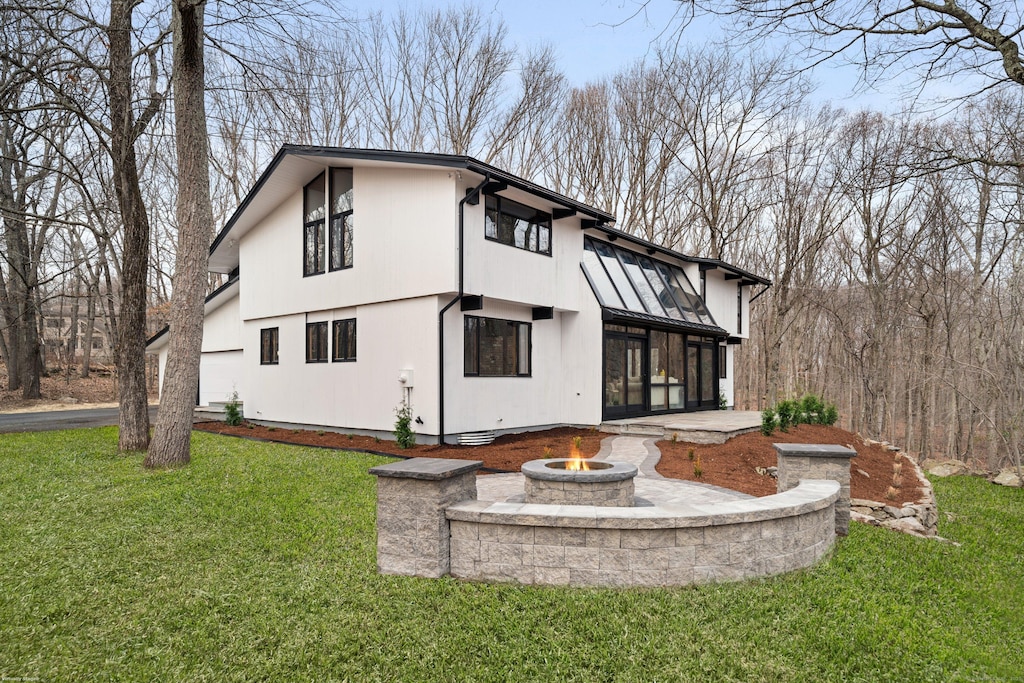 rear view of house featuring a standing seam roof, a fire pit, metal roof, and a yard