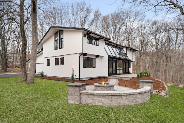 rear view of house featuring a standing seam roof, a fire pit, metal roof, and a yard