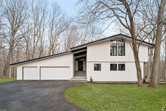 view of front of home featuring an attached garage, driveway, and a front lawn