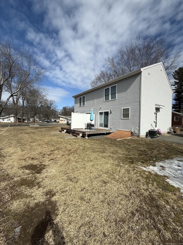 rear view of property with central air condition unit, a deck, and a yard