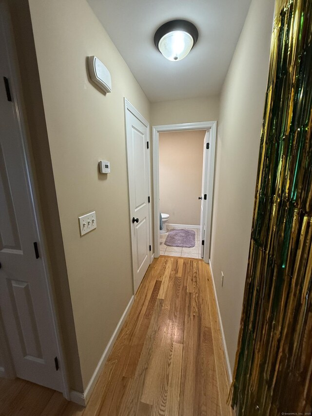 hallway featuring light wood-style floors and baseboards