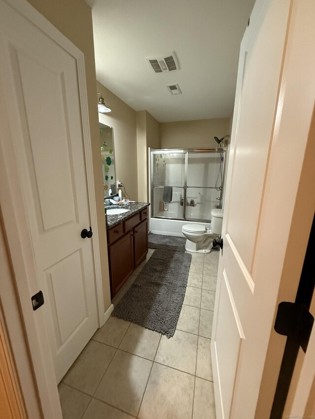 full bathroom with toilet, shower / bath combination with glass door, vanity, visible vents, and tile patterned floors