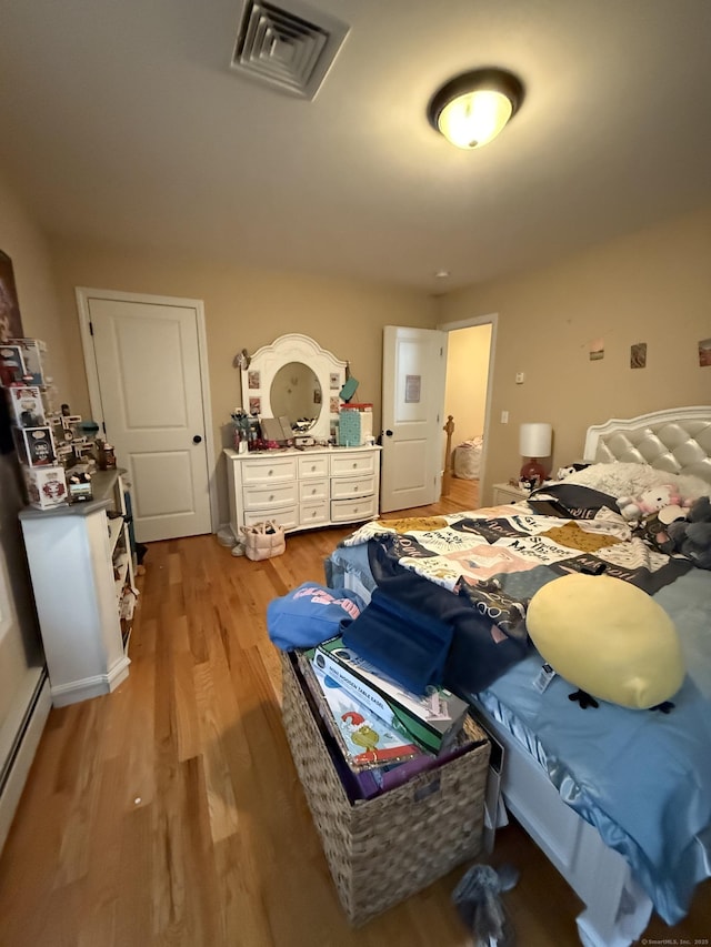 bedroom featuring light wood-style floors, visible vents, and baseboard heating