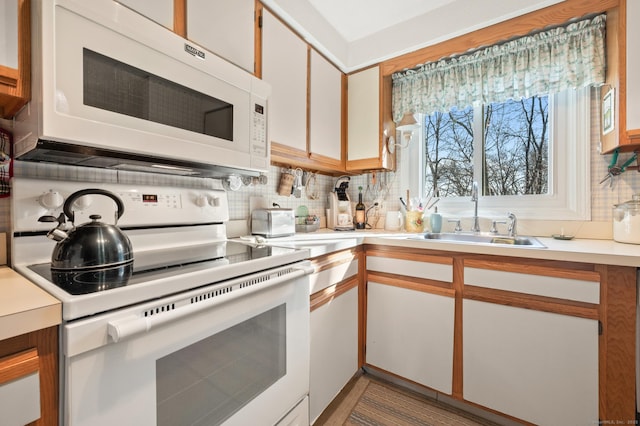 kitchen featuring light countertops, white appliances, backsplash, and a sink