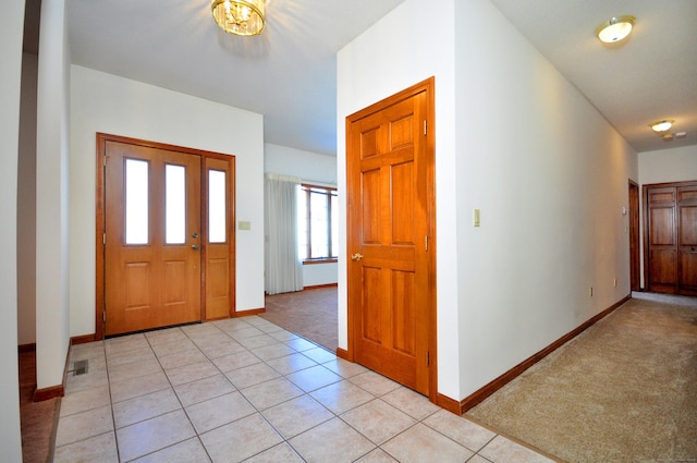 foyer featuring light tile patterned flooring, baseboards, visible vents, and light colored carpet