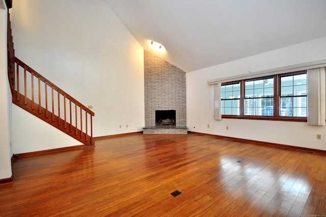 unfurnished living room featuring a fireplace, wood-type flooring, visible vents, baseboards, and stairs