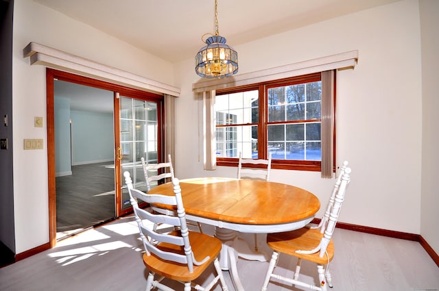 dining area featuring a wealth of natural light, a notable chandelier, baseboards, and wood finished floors