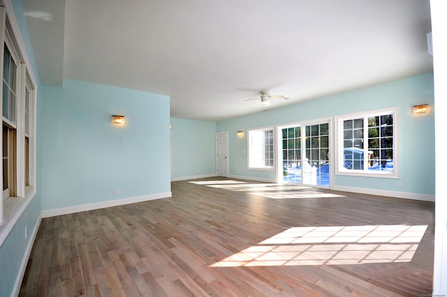 unfurnished living room with ceiling fan, baseboards, and wood finished floors