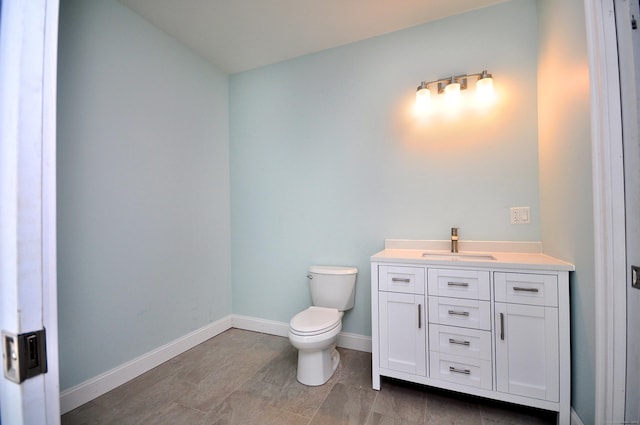 bathroom with toilet, baseboards, and vanity