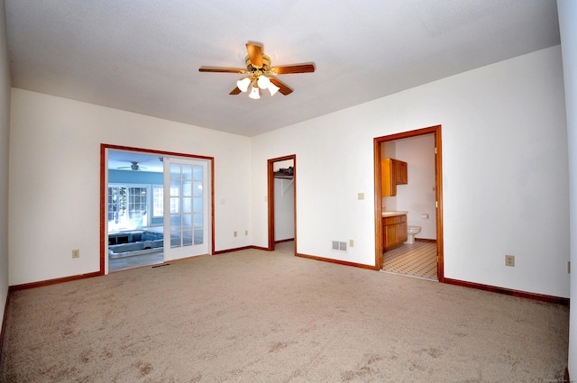 empty room with light colored carpet, visible vents, ceiling fan, and baseboards